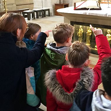 Referentin Stephanie Sczepanek zeigt den Kommunionkindern die goldenen Apostelstatuen im Altar des St.-Paulus-Doms.