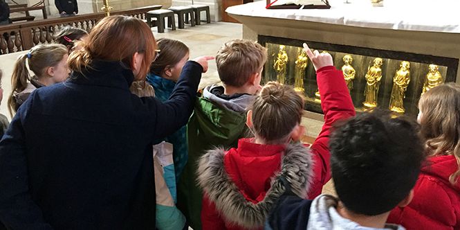 Referentin Stephanie Sczepanek zeigt den Kommunionkindern die goldenen Apostelstatuen im Altar des St.-Paulus-Doms.